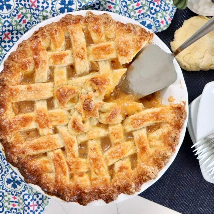 Golden lattice-top peach pie fresh out of the oven with filling bubbling through the crust