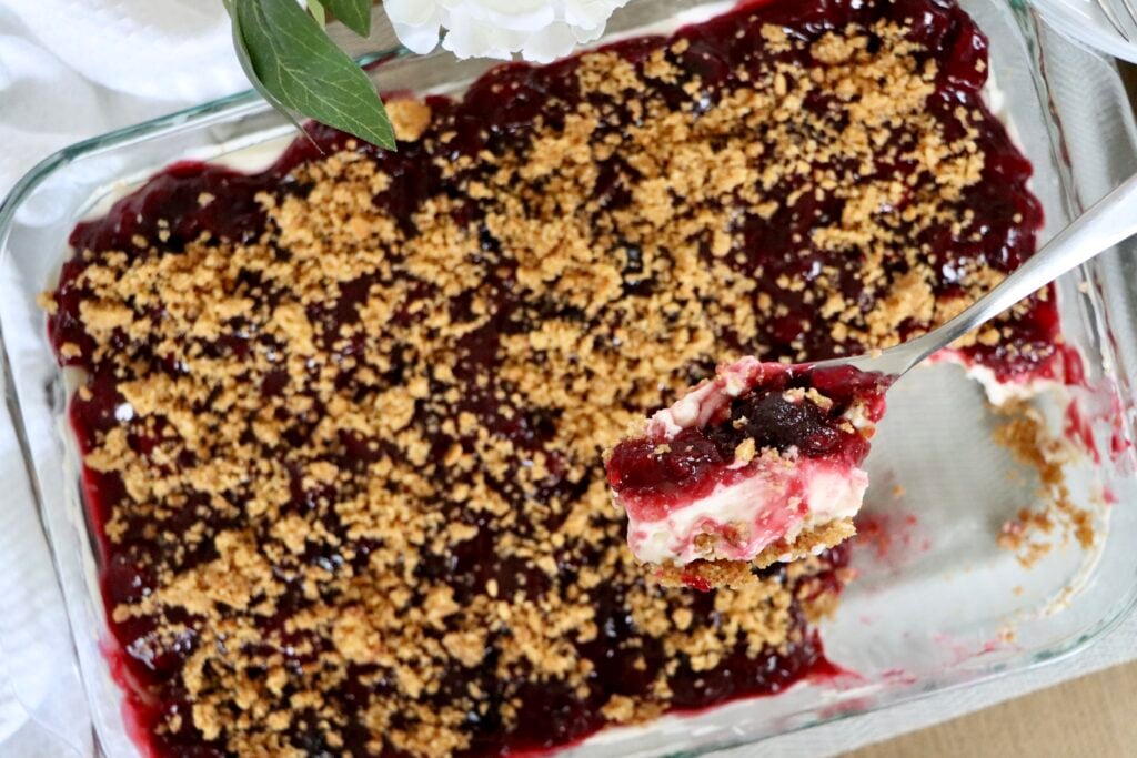 Close-up cross-section of cherry yum yum showing graham cracker crust, whipped cream cheese, and cherry filling layers