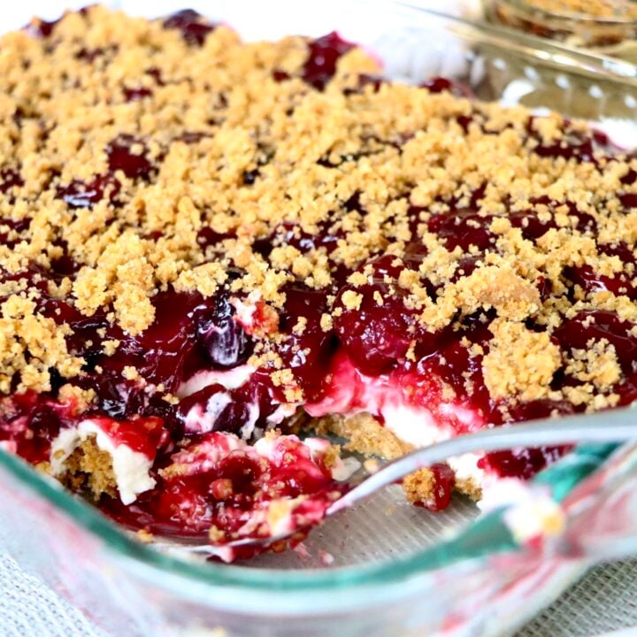 Close-up cross-section of cherry yum yum showing graham cracker crust, whipped cream cheese, and cherry filling layers