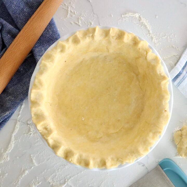 Unbaked pie crust crimped by hand around the edge of a pie plate