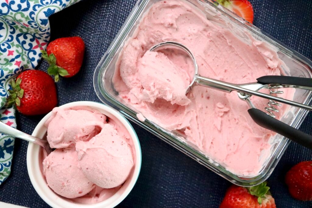 Overhead shot of homemade strawberry ice cream in a white bowl with a spoon