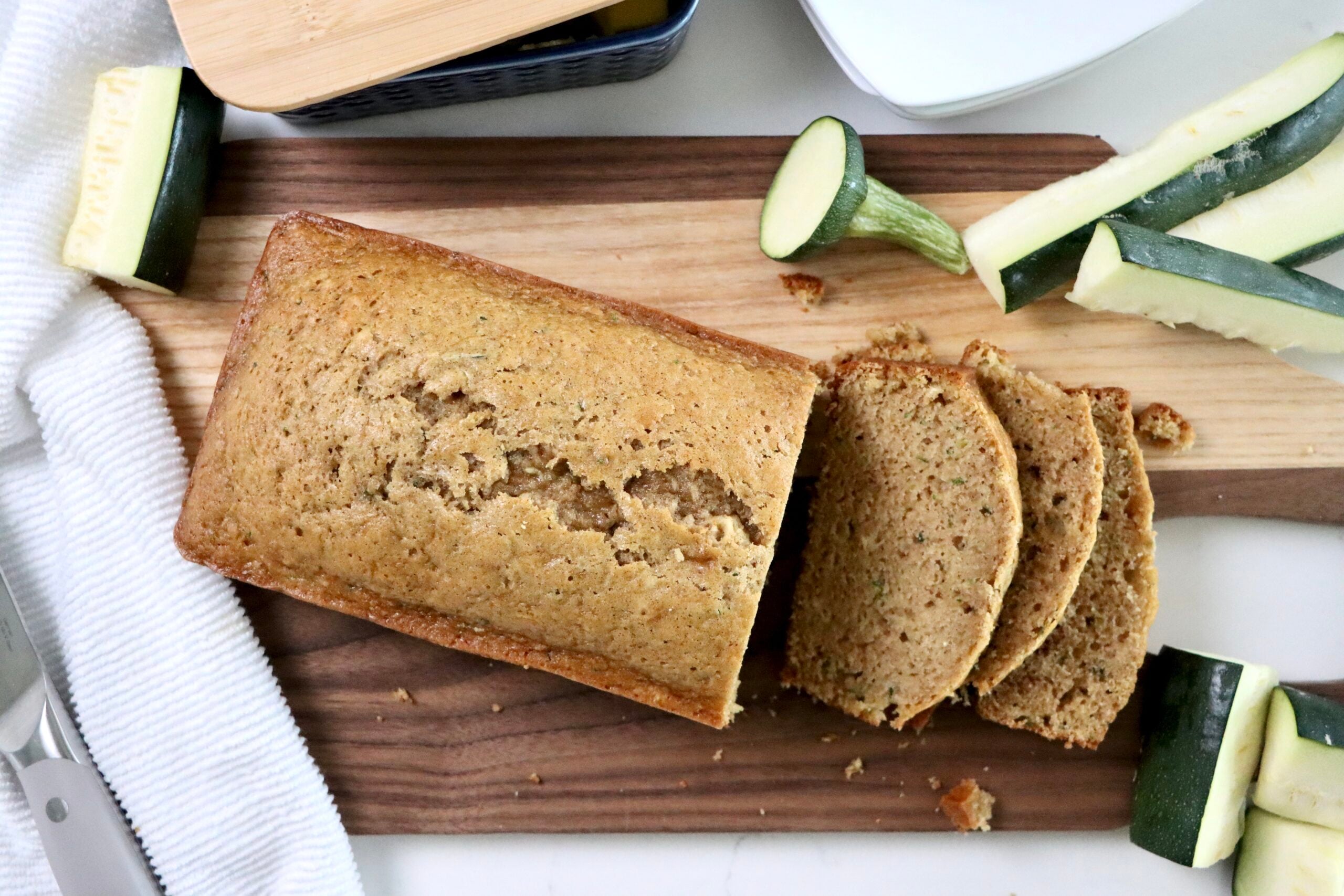 Zucchini bread loaf sliced and arranged on a rustic serving board