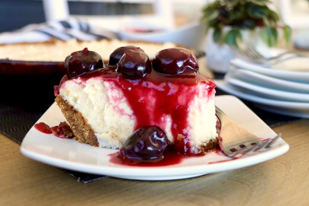 Close-up of cherry cream cheese pie slice showing gingerbread crust, filling, and cherry topping layers