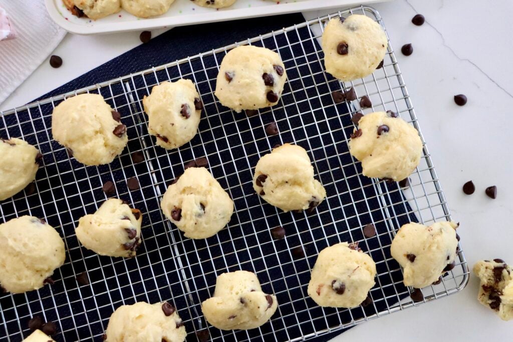 Mini chocolate chip muffins on a cooling rack with melted chocolate chips visible on top