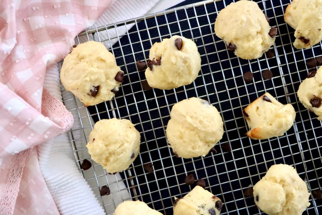 Mini chocolate chip muffins with domed bakery-style tops cooling on a wire rack