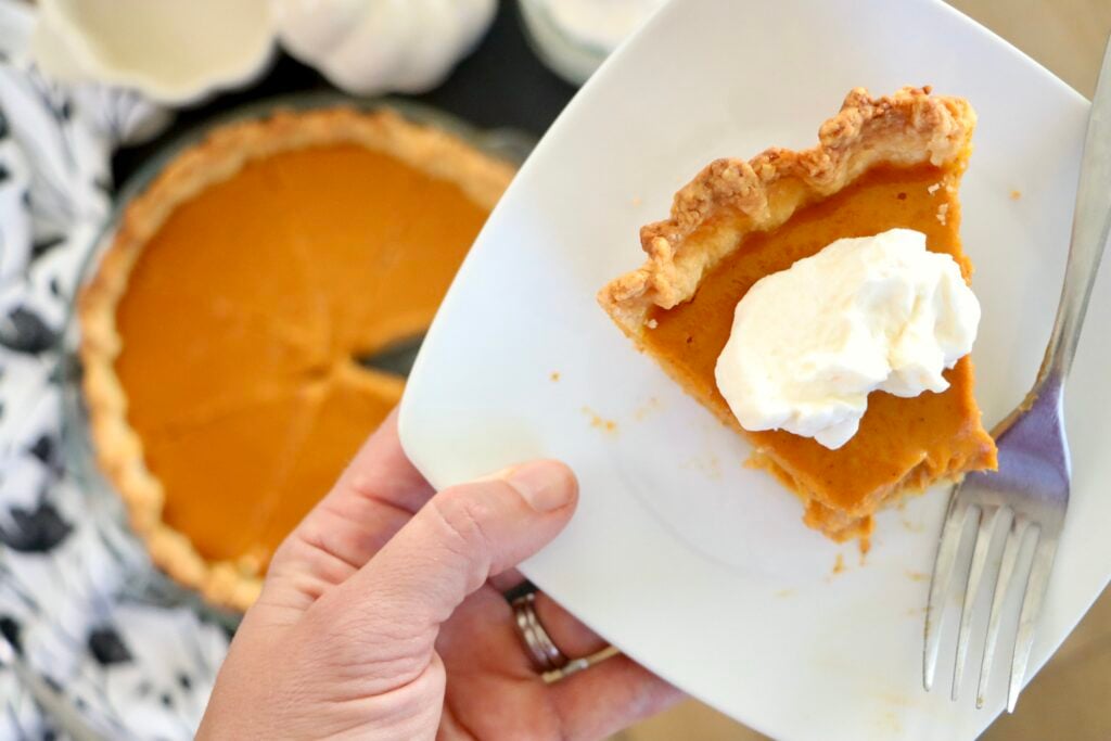 Slice of homemade pumpkin pie with a flaky Greek yogurt crust on a white plate